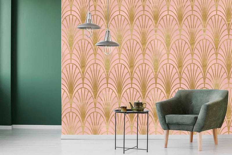A modern room features a light pink and gold art deco patterned wallpaper. The intricate design incorporates soft, pastel pink hues complemented by luxurious gold details, forming geometric shapes that evoke the elegance of the Art Deco movement. This refined color palette and sophisticated pattern are perfect for adding a touch of vintage glamour to any space.