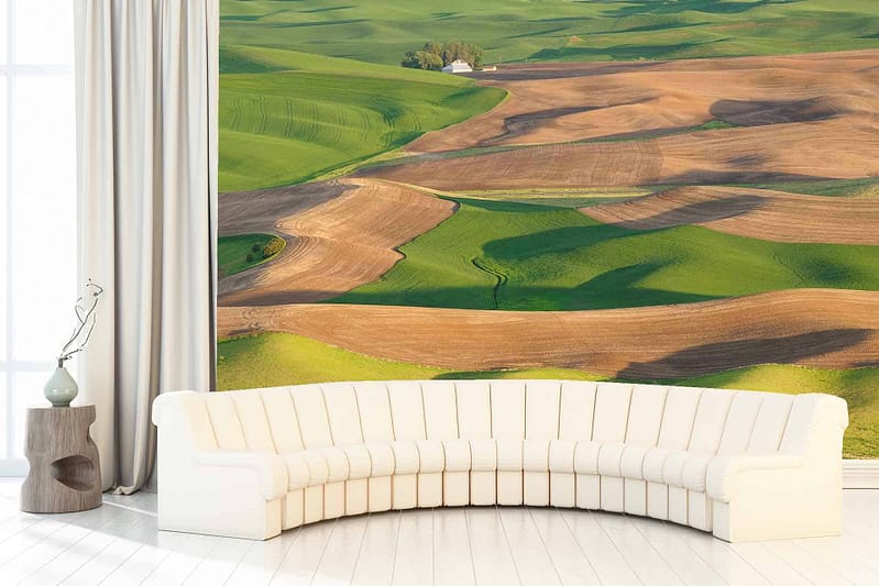 Wall-sized mural with vast, lush landscape. Green and brown fields dominate the scene. Natural tones blend harmoniously. Expansive, depicting nature's untouched beauty. Vivid greens represent fertile ground; darker browns highlight terrain variation. Rich color palette evokes tranquility and depth.