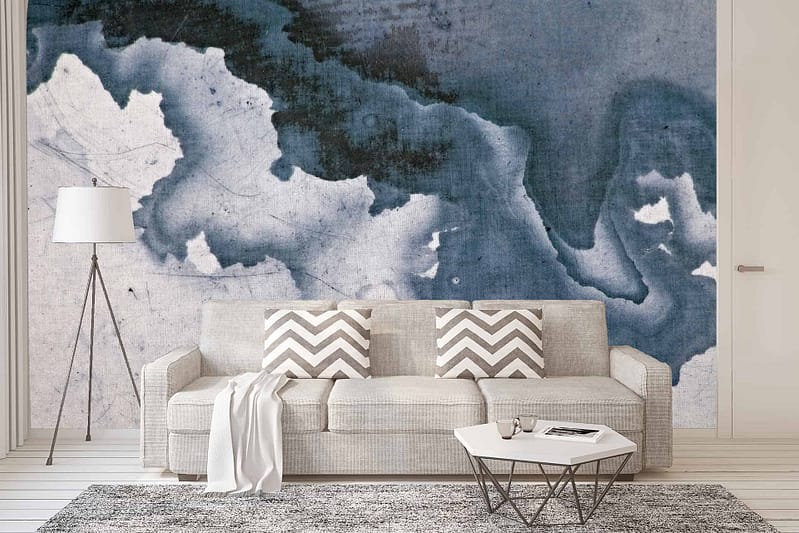 The backdrop features an abstract mural resembling an ink cloud formation in shades of blue and white. Elements include fluid, swirling patterns, with various blues blending seamlessly into white, creating a mesmerizing and dynamic focal point. The design evokes movement and depth, reminiscent of watercolor or cloud-like dispersion.