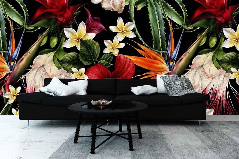 A modern living room boasts a vibrant, bold floral mural with tropical flowers and greenery. The wallpaper features an array of colors including vivid reds, lush greens, and bright yellows against a dark backdrop. This eye-catching design creates a striking focal point in the space.