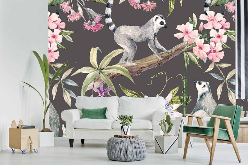 The wallpaper features a vibrant, large mural of lemurs perched on branches. Surrounding them are bold hibiscus flowers in reds and pinks, along with an array of lush tropical leaves in various shades of green. The design captivates with its dynamic composition and rich color palette.