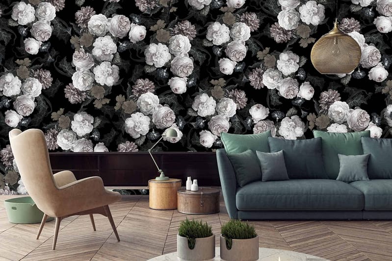 A modern living room features a large floral wall mural showcasing white and gray flowers set against a dark background. This wallpaper creates a striking "lost and found" aesthetic with contrasting light and dark elements.