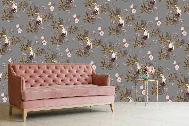 A wall covered in grey floral and tropical bird patterned wallpaper, featuring detailed illustrations of exotic birds in vibrant shades of red, blue, and yellow amidst lush foliage and ornate blossoms in soft hues like peach and cream.