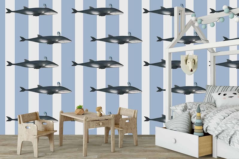 The children's room is adorned with a blue and white striped wallpaper featuring whimsical whale illustrations. The wallpaper's stripes alternate between soothing shades of blue and crisp white, creating a calm yet playful atmosphere. Scattered across the stripes are charming illustrations of gentle whales in various sizes and poses, adding a touch of marine magic to the space. This aquatic-themed wallpaper captures the essence of the sea with its serene color palette and delightful whale motifs, making it perfect for fostering imaginations filled with gentle whale songs.