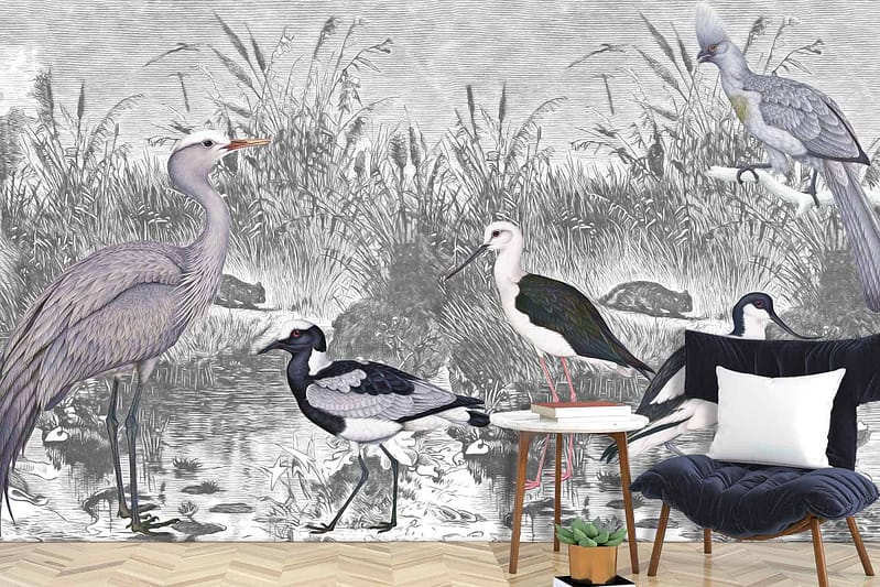 A sophisticated mural showcases wading birds such as herons and cranes amidst a serene wetland scene. The design features a monochromatic palette, emphasizing shades of gray, black, and white to depict the natural elements like water, reeds, and distant trees. This wallpaper combines elegance with a nature-inspired aesthetic.