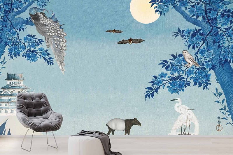 A serene mural wallpaper features a moonlit scene with blue-toned trees, a peacock flying, bats in the sky, a snowy owl perched on a branch, and a tapir, flamingos, and a chair in the foreground. A castle is visible in the background. The predominant colors include various shades of blue and white.