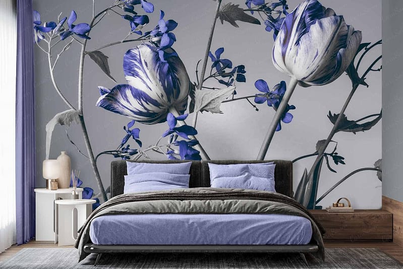 The bedroom features a striking mural wallpaper behind the bed. The wallpaper displays an array of large blue and white flowers, with delicate shades of blue intermingling with pristine white petals. This floral design is prominent and instantly eye-catching, creating a serene yet vibrant focal point in the room. The varying hues of blue—from soft pastels to deeper tones—add depth and interest, while the pure white elements provide a fresh, clean contrast.