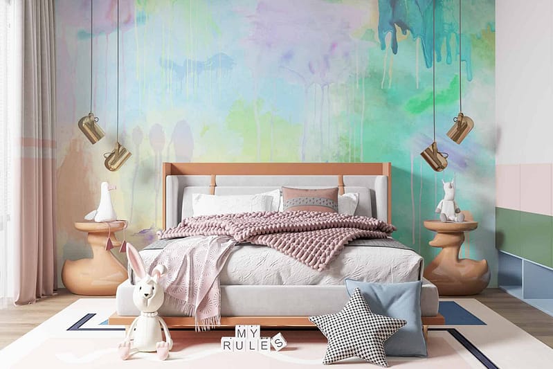 The wallpaper is a large abstract mural with dripping paint effects. It features vibrant colors including pastel hues such as soft pink, baby blue, mint green, and sunny yellow. The design is whimsical and playful, adding to the room's joyful atmosphere.
