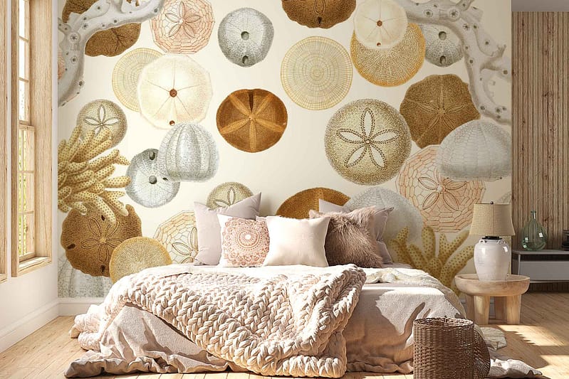 The wallpaper behind the bed showcases various sea urchins, sand dollars, and coral patterns in neutral tones. Elements include intricate sea urchin designs with detailed textures, sand dollars featuring characteristic star-like imprints, and branching coral motifs. Colors range from beige and taupe to soft grey and off-white, creating a serene marine-inspired backdrop perfect for a cozy bedroom setting.
