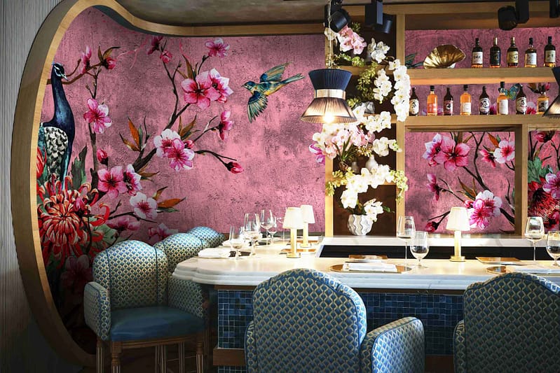 The wallpaper features intricate floral designs and vibrant bird motifs, creating a serene and nature-inspired escape. Elements include blooming flowers and perched birds in shades of blue, white, green, and occasional hints of yellow.