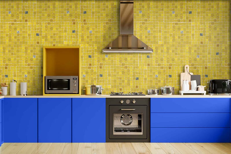 The wallpaper features a dynamic pattern of vibrant yellows and blues, creating depth with varying shades. Key elements include bold geometric shapes, subtle floral motifs, and intricate lines that echo the kitchen's vivid blue cabinets and yellow mosaic tile backsplash. The color palette perfectly harmonizes with the kitchen's modern aesthetic, offering a lively and cohesive look.
