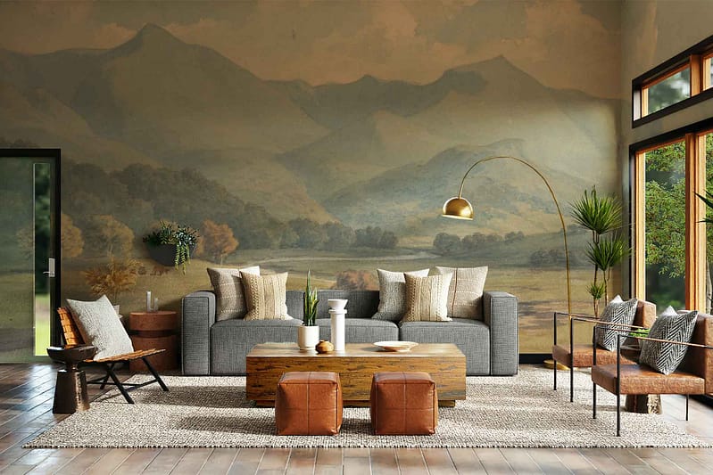 The mountain mural wall is the standout feature of this stylish living room, embodying the "Way Down" aesthetics with its serene and earthy elements. The wallpaper showcases towering mountain peaks in varying shades of gray and deep charcoal, blending seamlessly into softer hues of misty blue at the base. Rich forest greens accentuate the lower slopes, adding depth and an organic touch. Subtle layers of white depict snow-capped summits, creating a striking contrast against the darker tones. This mural brings nature's grandeur indoors, perfectly harmonizing with the room's contemporary furnishings and rustic wooden flooring through its neutral yet impactful color palette—gray, charcoal, misty blue, forest green, and white.
