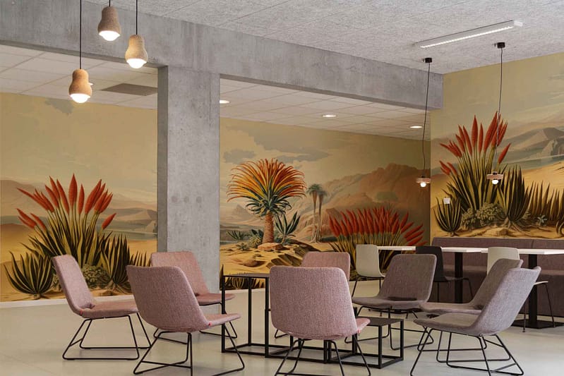 Desert-themed wallpaper featuring vibrant desert plants, cactus motifs, sandy dunes, succulent greenery and muted earth tones. Predominantly soft pinks, greens, beiges with touches of bright blooms stand out.