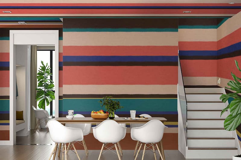 A modern dining room features a bold accent wall with vibrant horizontal stripes in various colors, creating visual interest. The wallpaper's colorful lines include shades of red, blue, green, yellow, and orange.