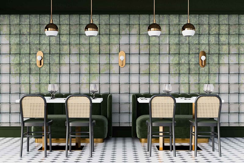 The wallpaper, reminiscent of elegant Glass Houses, features a lush botanical theme with an emerald green backdrop. It showcases intricate patterns of large, overlapping leaves in varying shades of green, accented with touches of white and gold to add depth and luxury. The design is meticulously detailed with hints of geometric lines interwoven between the foliage, creating a harmonious blend that complements the restaurant's art deco elements. Look for keywords: botanical theme, emerald green backdrop, intricate leaf patterns, shades of green, white accents, gold accents and geometric lines.