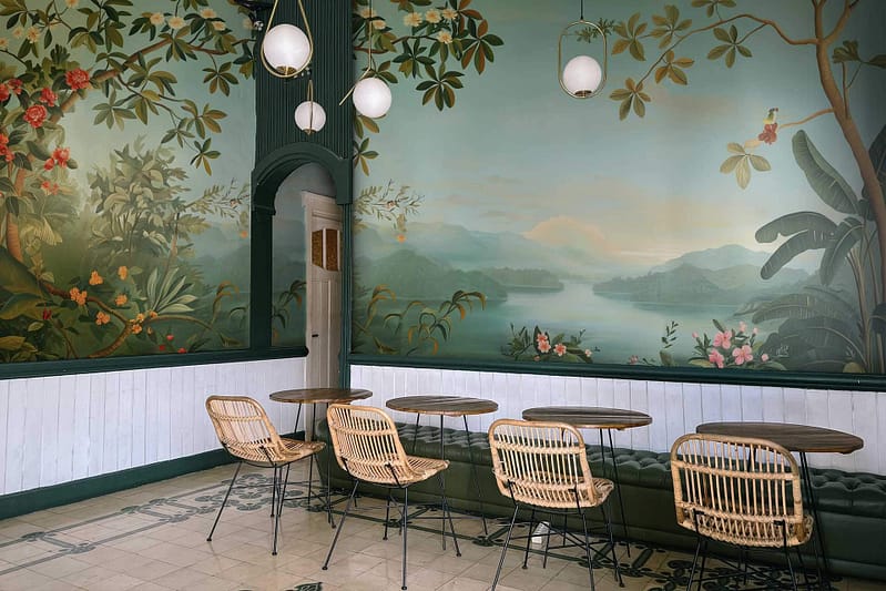 Golden Hour mural features a lake, mountains, painted trees, and flowers. Warm hues of orange, pink, and gold illuminate the scene.