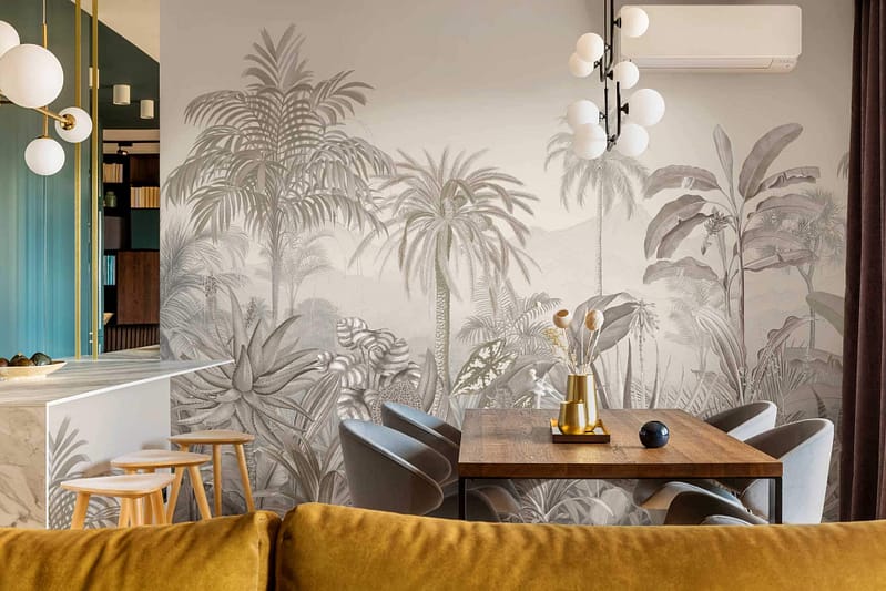 The wallpaper features a large, detailed jungle-themed mural in varying shades of gray, highlighting intricate tropical leaves, plants, and exotic flora. The monochromatic color palette adds depth and sophistication, creating a textured and immersive backdrop. Keywords: jungle-themed mural, shades of gray, tropical leaves, exotic flora.