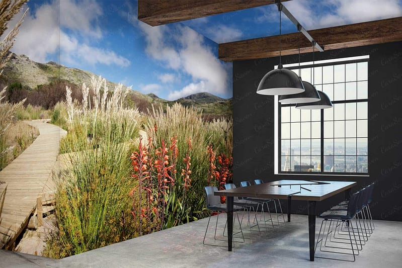 Mural wallpaper: wooden boardwalk, lush grassy landscape, mountains in the background, red wildflowers in the foreground.