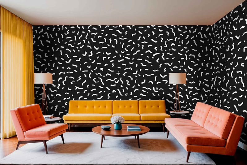 A modern living room features a bold black and white patterned accent wall, characterized by intricate geometric shapes and high contrast. The wallpaper showcases elements such as chevrons, stripes, or abstract forms in striking black against a crisp white background. This dynamic design acts as the focal point of the space and adds visual interest to the overall decor.