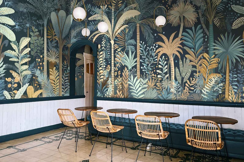 The wallpaper at Davis's stylish café features bold, leafy patterns with vibrant greens reminiscent of tropical plants.
