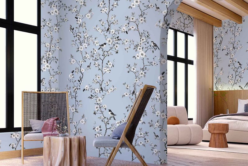 The wallpaper features a vibrant design with intricate floral patterns and delicate birds perched among the branches. The colors include lush greens, soft pinks, deep blues, and subtle yellows, set against an off-white background. The detailed illustrations capture a sense of nature's beauty with blooming flowers and graceful birds in flight, adding elegance and a touch of whimsy to any room. Perfect for an interior seeking a harmonious blend of nature-inspired elements.