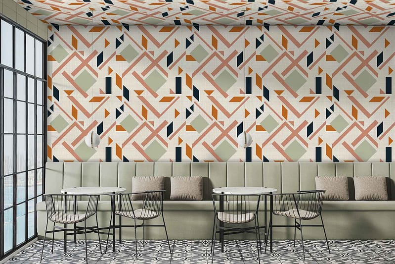 The wallpaper in the modern café interior showcases geometric patterns in vibrant green, orange, and black. These colors create a lively and dynamic contrast on the walls and ceiling. The geometric shapes in the design are bold and varied, making them stand out as key elements of the décor.