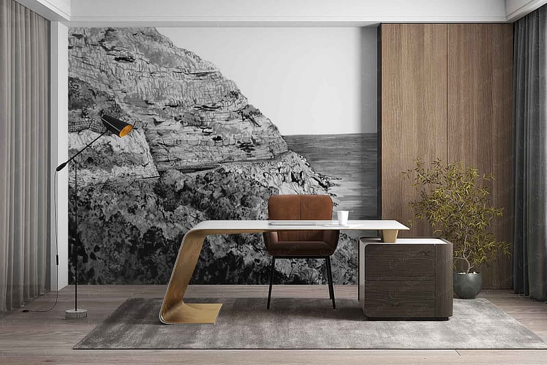 Large mural wallpaper depicting rugged rocky cliffs beside a deep blue sea, with dramatic stone textures in muted grays and browns. Hints of green foliage on cliff edges and an expansive, cloudy sky above in soft blue and gray tones. Coastal, natural landscape scene.