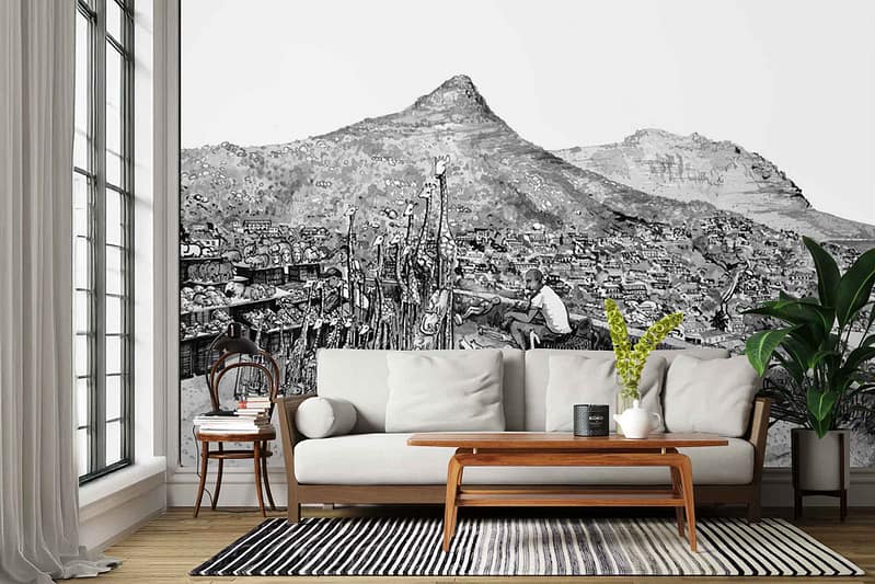 ZEITZ 02 wall mural: black-and-white wallpaper featuring a striking mountain landscape blended with a detailed cityscape; includes artistic linework of buildings, rugged peaks, and a prominent figure of a person actively drawing, all in monochrome tones.