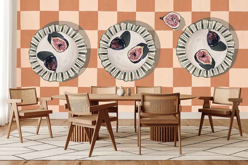 Peach and beige checkerboard wallpaper featuring large painted plates, figs, and bright citrus fruits. Bold colors and picnic-inspired elements stand out on the patterned wall.