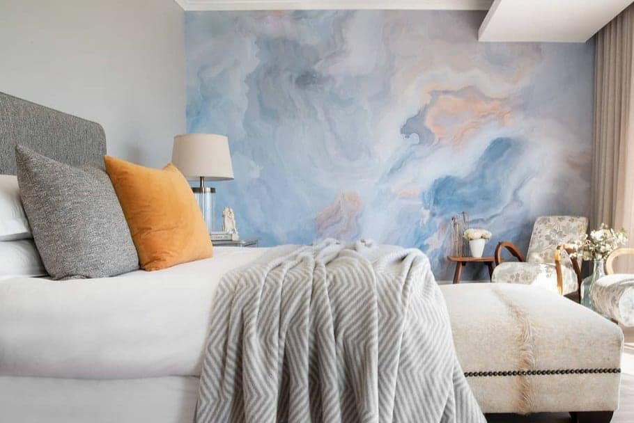 A striking blue and pink abstract wall mural graces the modern bedroom, featuring elements of swirling patterns and bold hues. The vivid blend of blue and pink creates a captivating focal point, enhancing the serene ambiance.