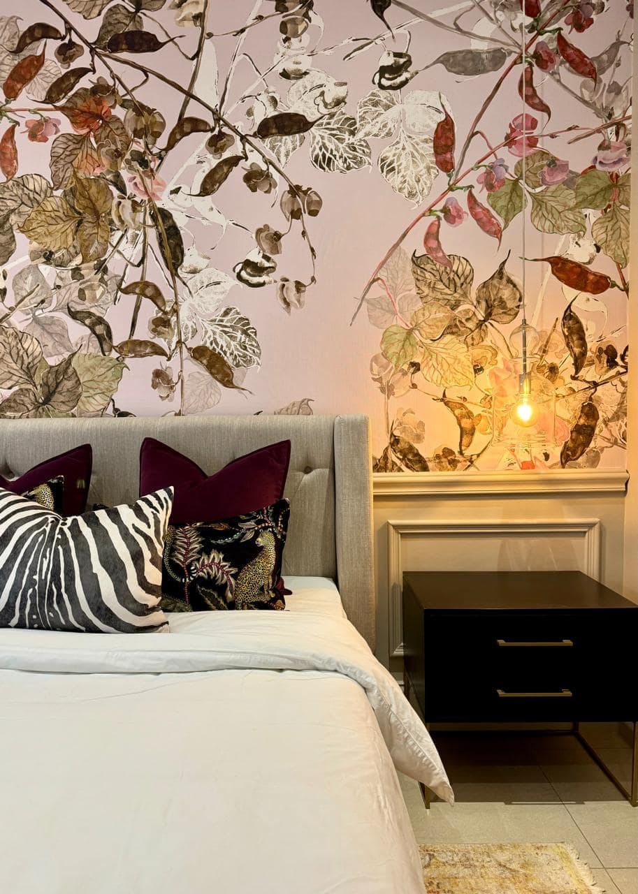 The wallpaper is a striking floral mural featuring intricate botanical designs in shades of deep green, blush pink, and soft cream. Perfect for adding an elegant touch to any room.