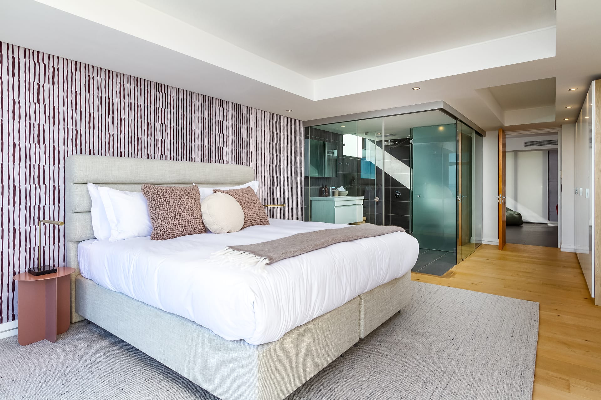 Textured accent wallpaper features a subtle geometric pattern in soft taupe and light gray tones, adding visual depth with matte and slightly metallic finishes. The design incorporates overlapping lines and raised surfaces, creating a modern, tactile effect that pairs seamlessly with neutral decor.