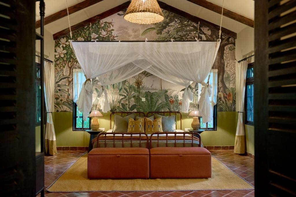 Tropical-themed wall mural with vibrant green palm leaves, lush foliage, and touches of bright florals in pink and yellow tones. The wallpaper features dense jungle patterns, creating an exotic atmosphere.