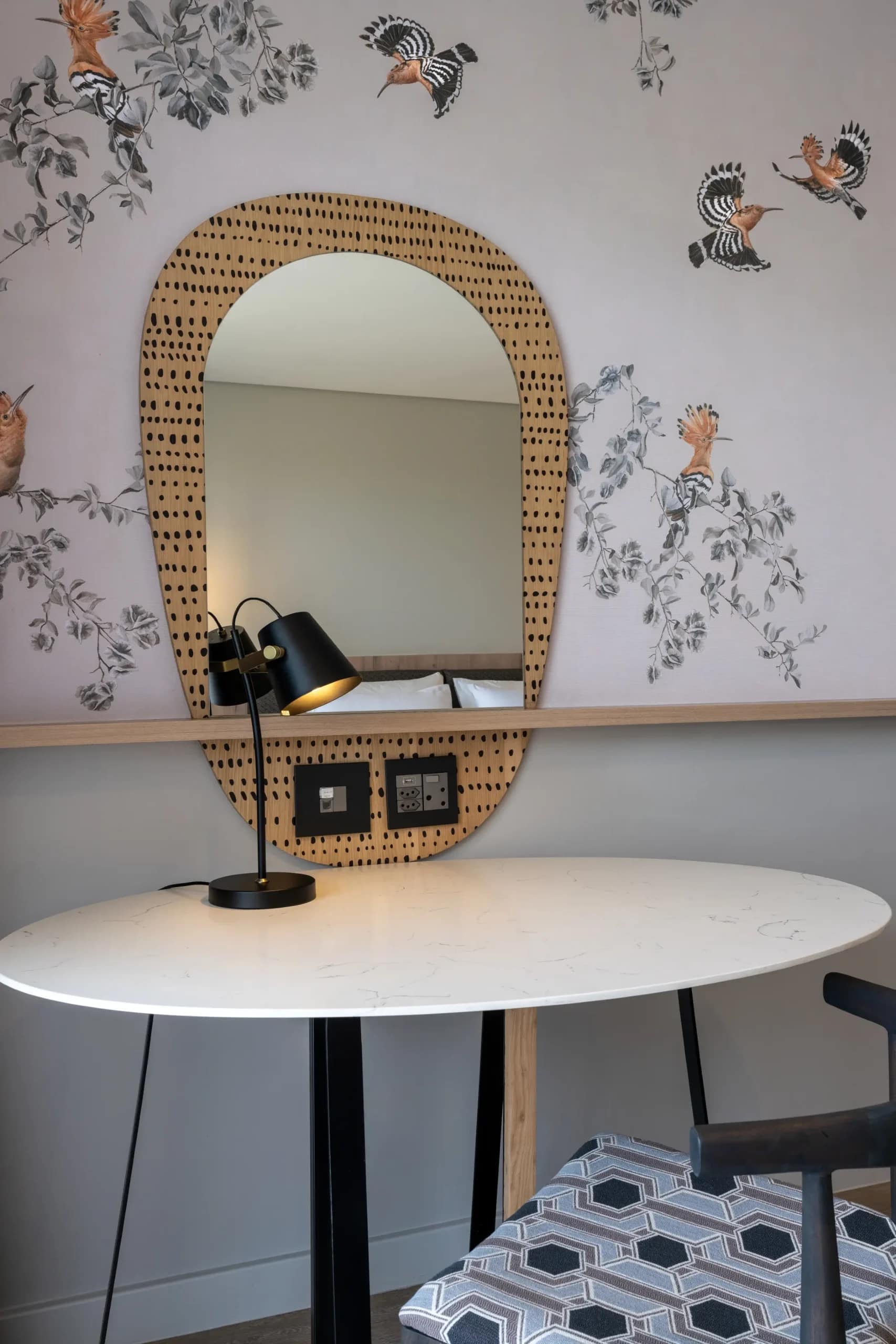 Wallpaper with birds and floral designs in various colors, featuring detailed flowers and perched birds on leafy branches. The pattern includes soft greens, blues, pinks, and yellows, creating a vibrant yet elegant backdrop.