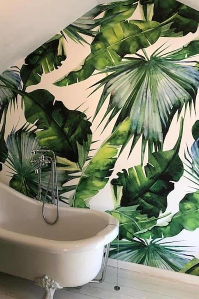 The wallpaper features vibrant green leafy patterns, creating a tropical, jungle-like atmosphere. The design includes various shades of green with detailed foliage, adding depth and exotic flair. This eye-catching feature infuses the space with nature-inspired elegance.