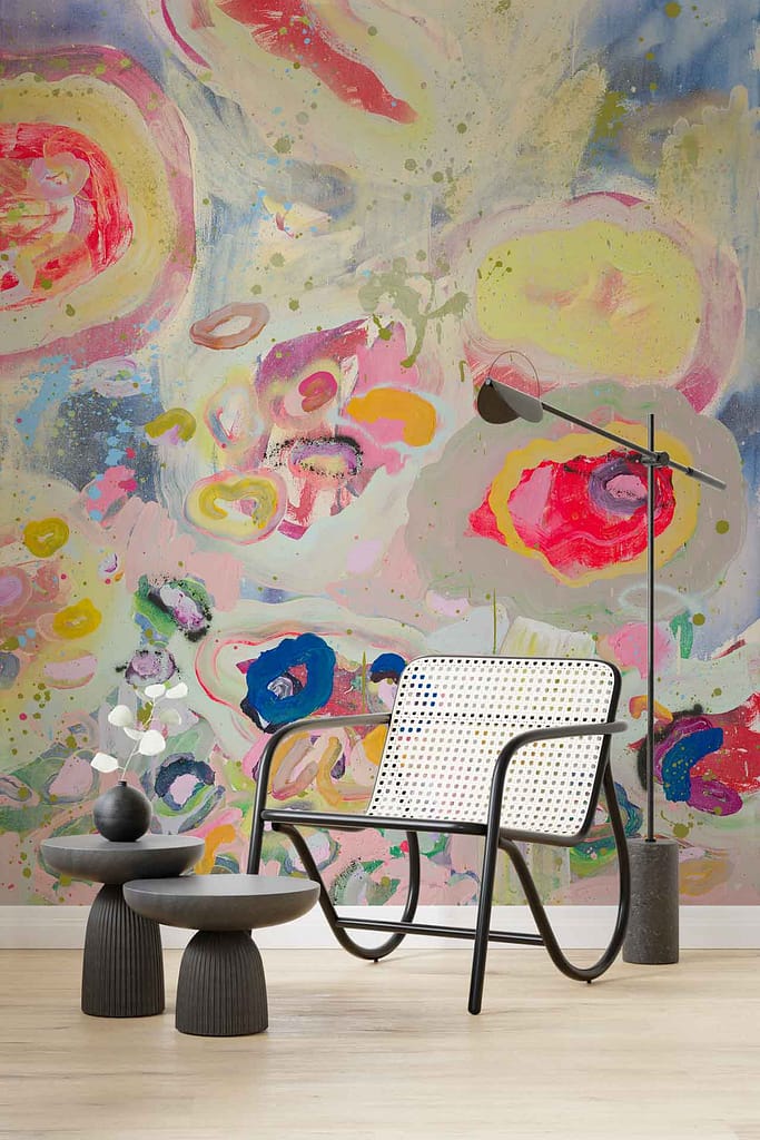 The wallpaper features a colorful abstract mural with swirling, vibrant patterns reminiscent of a dance performance. Dominant colors include bold reds, deep blues, bright yellows, and rich greens interwoven in fluid, dynamic shapes. Touches of purple and orange add depth and energy to the design. The patterns create a sense of movement and rhythm across the wall. Key elements are swirls, curves, and interlaced hues creating an eye-catching focal point that embodies motion and vibrancy.