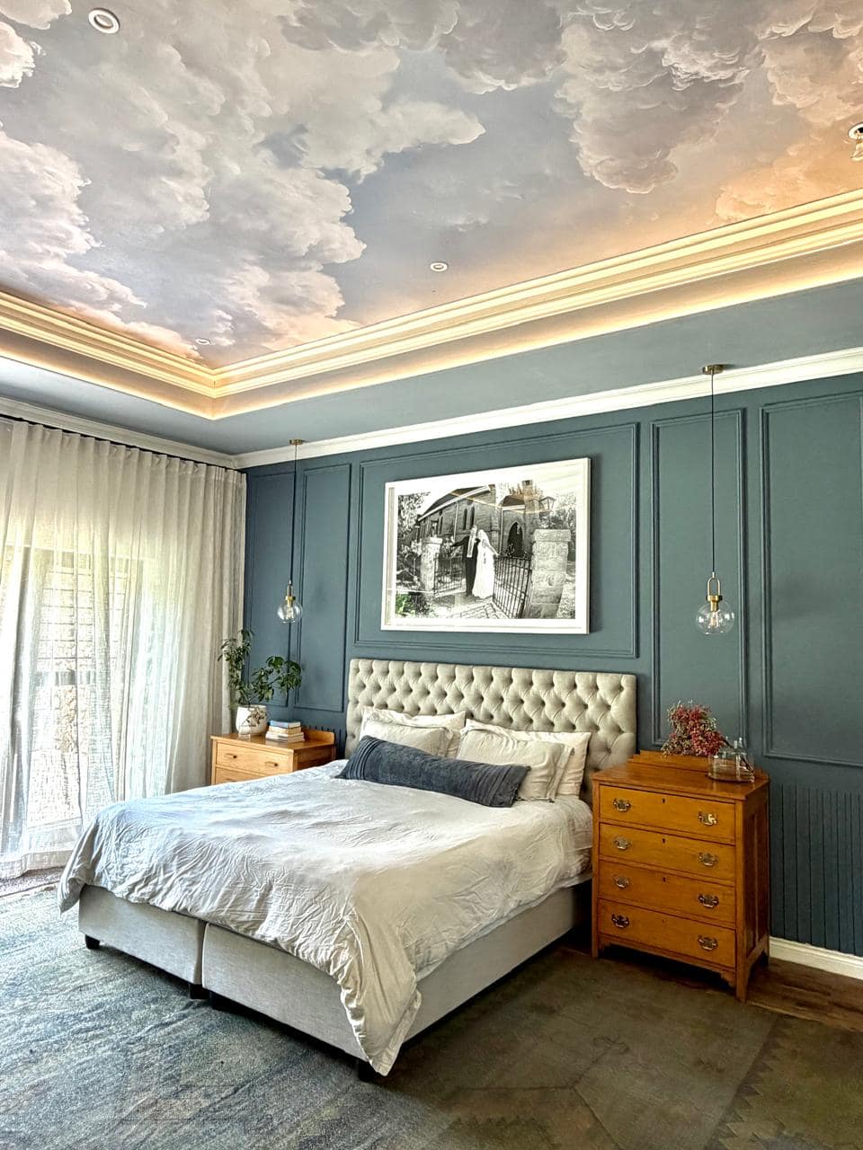 Painted sky wallpaper on the ceiling features soft blue tones with white, cloud-like patterns, creating an artistic and serene focal point for the room. Sky motif transforms the upper wall into a dreamy, atmospheric accent.
