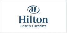 The wallpaper features a repeating pattern of a stylized "H" encircled, reminiscent of elegance and home. Dominated by bold blue hues, the elements create an inviting ambiance. The background includes subtle horizontal lines, enhancing the formal yet welcoming design. Look for deep blue colors and circular patterns when searching.