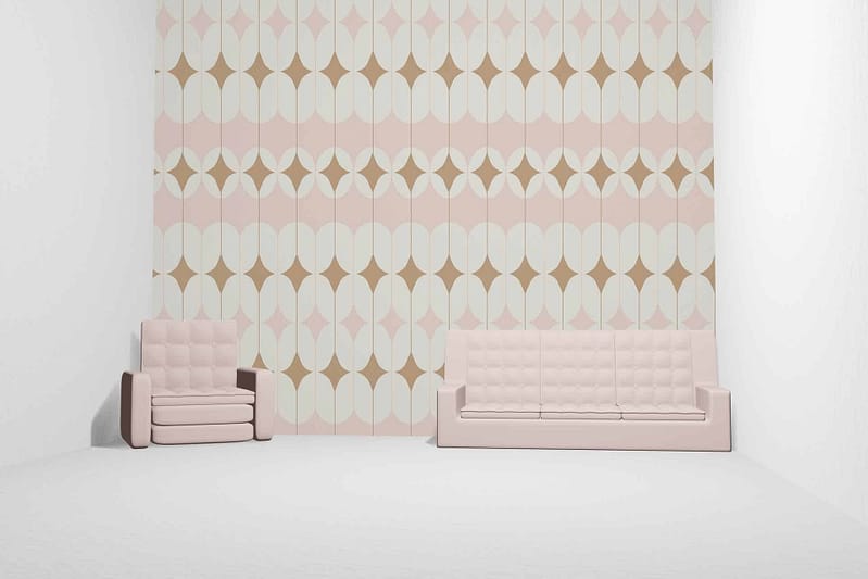 The minimalist room boasts a pastel-colored geometric wallpaper, featuring soft pink, cream, and tan shades. The design includes intersecting triangles and polygons in calming hues that blend seamlessly into the space’s aesthetic. The patterns are subtle yet distinct, creating a soothing ambiance perfect for relaxation and enjoying a quiet evening of Game of Thrones. This wallpaper's gentle colors—pastel pink, cream, tan—complement the light beige furniture and enhance the room's serene atmosphere.