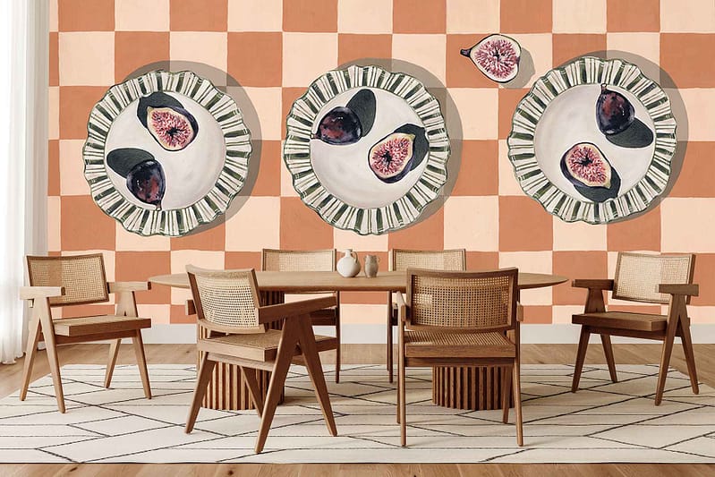 Peach and beige checkerboard wallpaper featuring large painted plates, figs, and bright citrus fruits. Bold colors and picnic-inspired elements stand out on the patterned wall.